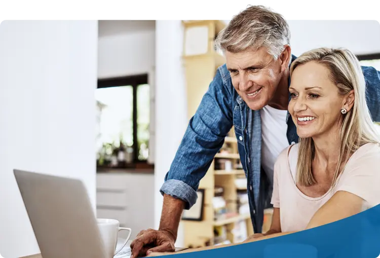 Smiling couple reviewing finances together on a laptop—symbolizing the security, planning, and legacy support offered through fiduciary and trust wealth management services.